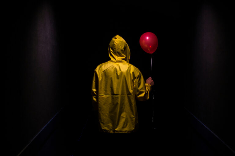 Hooded,Yellow,Figure,With,Red,Balloon,In,Dark,Creepy,Corridor